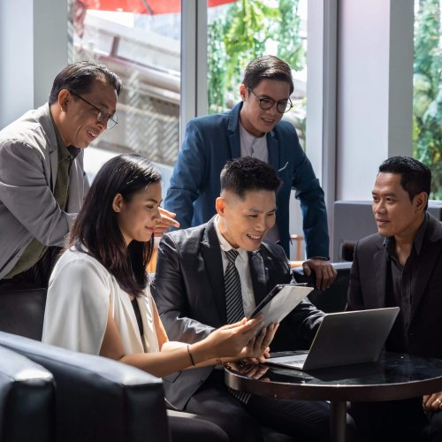 Asian business team wearing suit discussing and using computer in conference room. Diverse businesspeople working and sharing ideas concept on sofa in the office. business, people